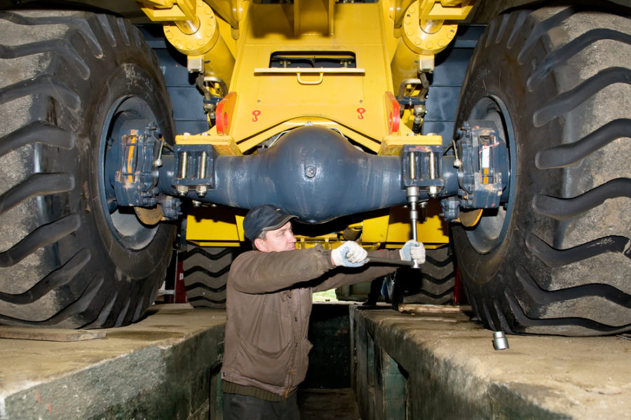 mechanic tightening bolts on a large construction machine