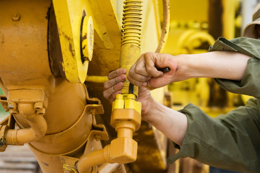 construction worker tightening blots on machine