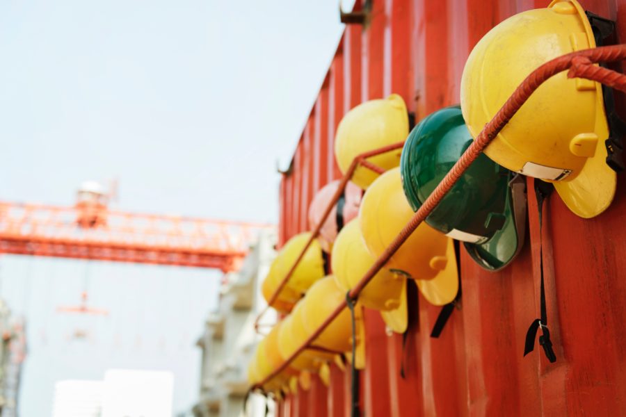 row of construction helmets hanging on a metal rod