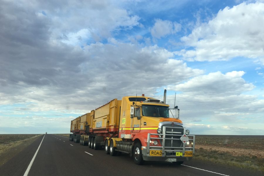 semi truck driving on highway with blue cloudy sky in background