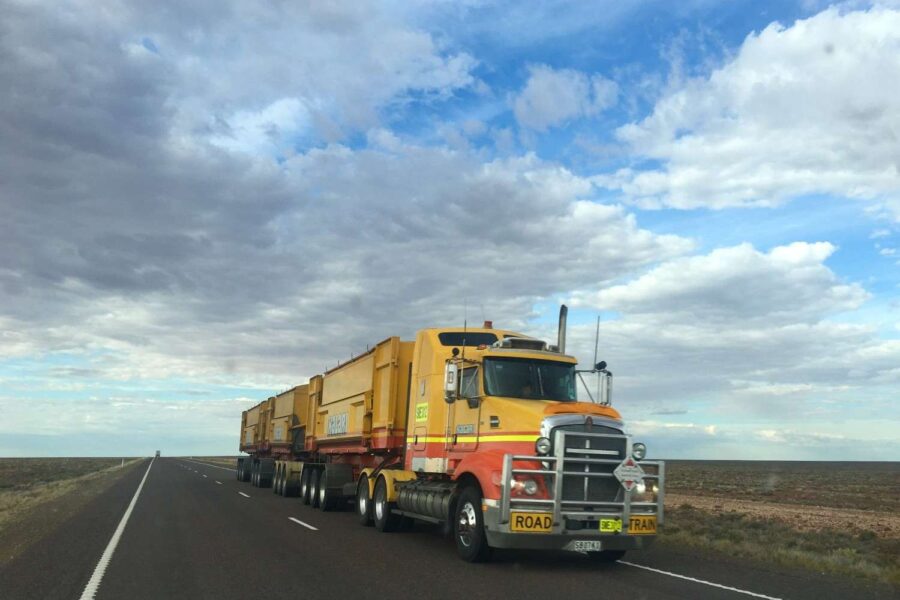front view of truck driving on road with cloudy sky in background