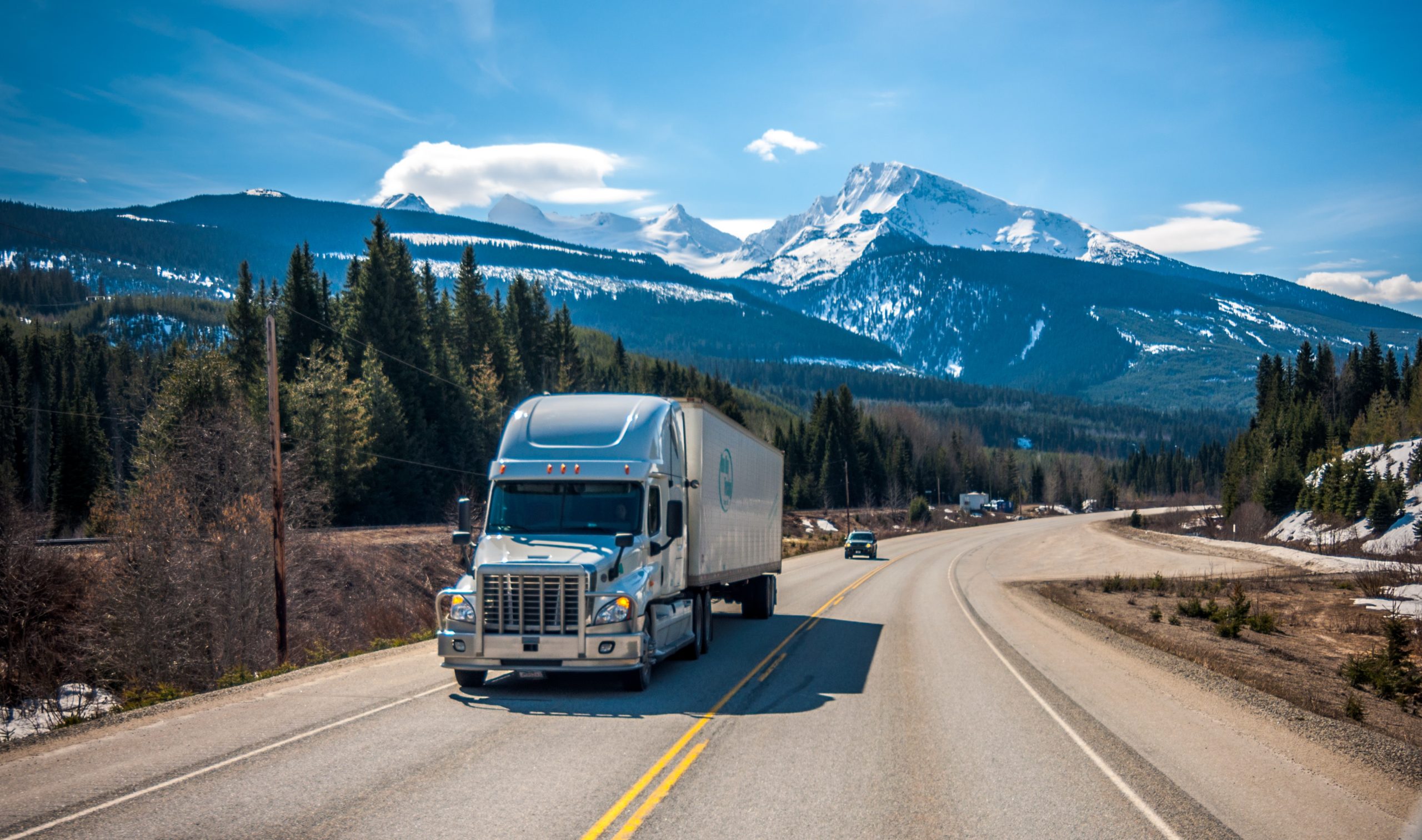 Front view of truck driving on road with mountains in the background 2