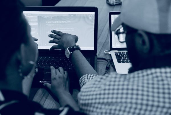 black and white photo of two people point at a computer monitor