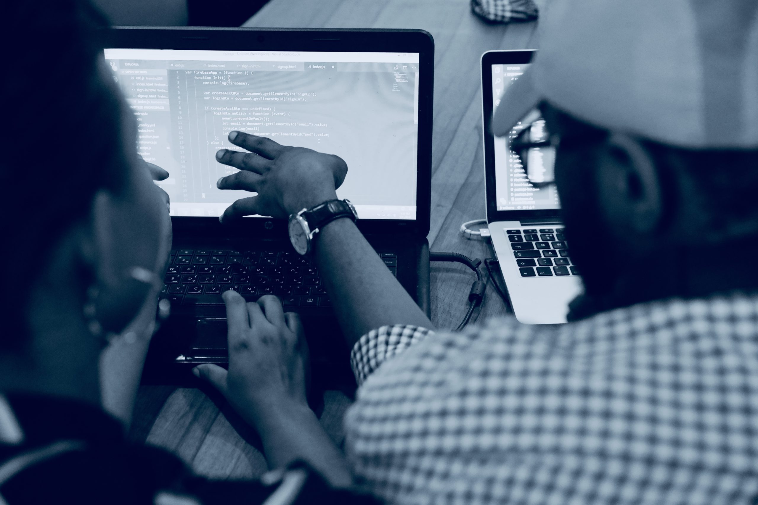 black and white photo of two people point at a computer monitor