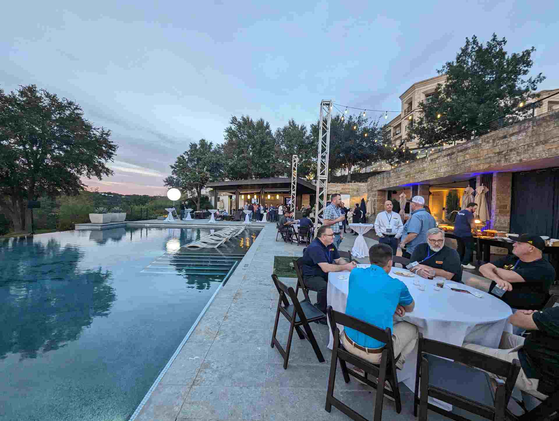 Guests enjoying dinner by poolside at sunset