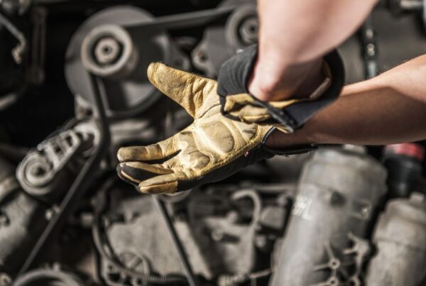 Service tech putting work gloves on to work on an engine