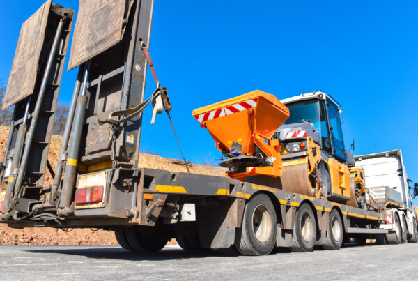 Schwertransporter transportiert eine Teerwalze auf einer neuen Straße