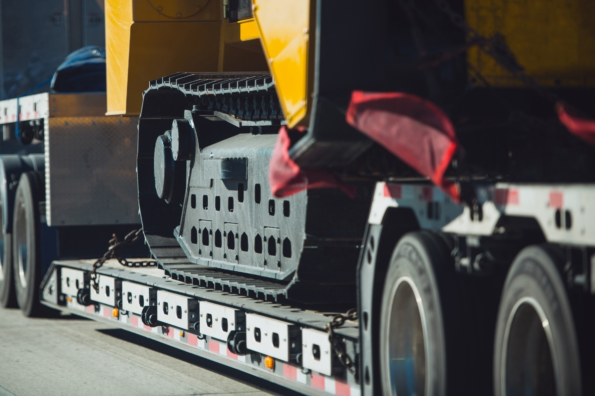 Tracked construction machine secured for transport with help from dispatch management software