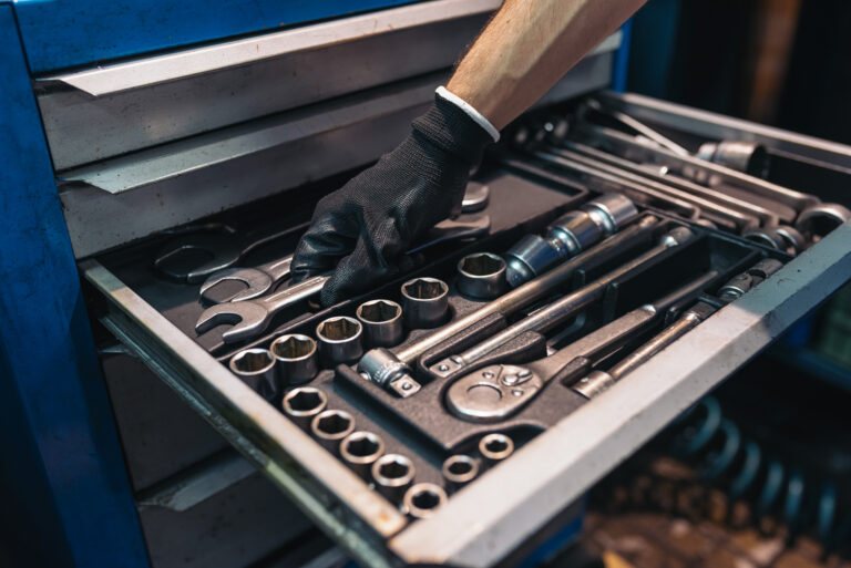 Technician selecting a wrench from tool drawer during work order maintenance task.