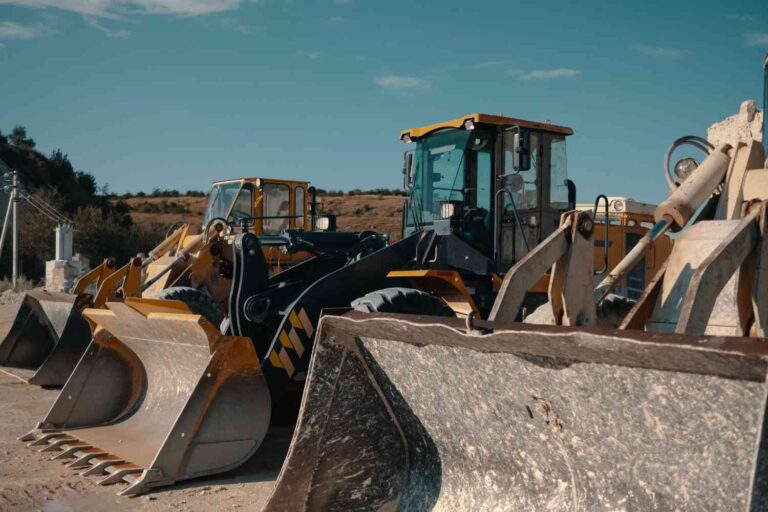 Row of heavy construction loaders parked in a rental yard